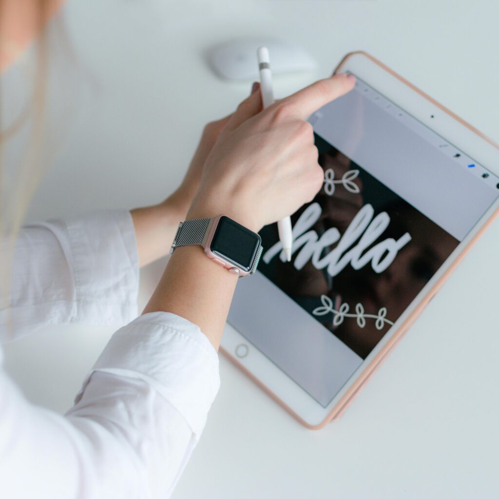 A woman interacts creatively with a tablet and stylus indoors, using technology for design.